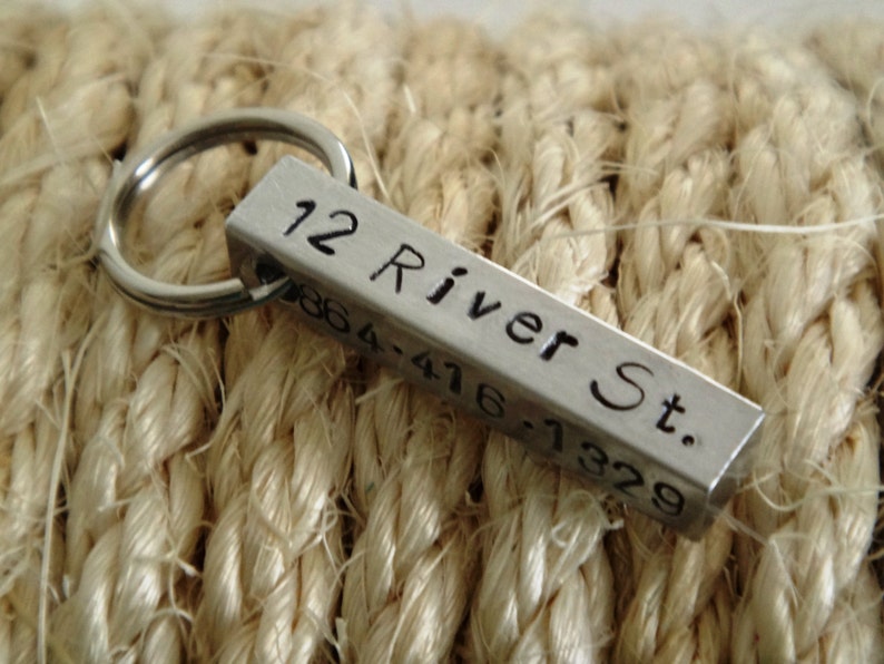 May include: Silver key chain with a rectangular tag engraved with "12 River St. 0864-416-7329".