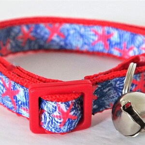 Peut inclure: Collier pour chat rouge et bleu avec une clochette argent&eacute;e. Le collier a une boucle rouge et un motif bleu et blanc avec des &eacute;toiles de mer rouges.