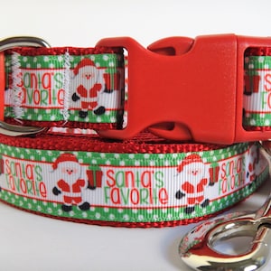 May include: Red and green dog collar and leash set with a white background featuring a repeating pattern of Santa Claus and the text "Santa's Favorite".