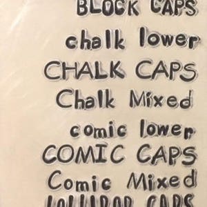 May include: A close-up of a sheet of clear plastic with various font styles printed on it. The text includes "angelina lower", "ANGELINA CAPS", "Angelina mixed", "BLOCK CAPS", "chalk lower", "CHALK CAPS", "Chalk Mixed", "comic lower", "COMIC CAPS", "Comic Mixed", "LOLLIPOP CAPS", "Posh lower", "POSH CAPS", and "Posh Mixed".