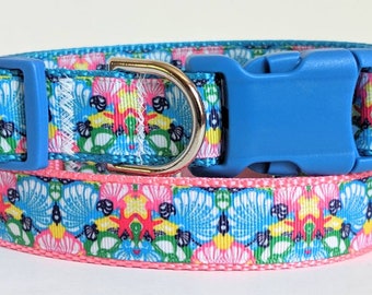 May include: A colorful dog collar with a blue buckle and a pink and blue patterned design featuring seashells and starfish.