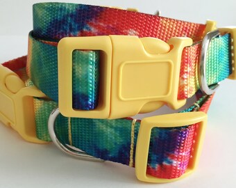 May include: A yellow and tie-dye dog collar with a yellow plastic buckle. The collar is made of a woven fabric with a tie-dye pattern in shades of blue, green, red, and yellow.