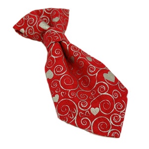 May include: Red bow tie with a silver swirl and heart pattern.