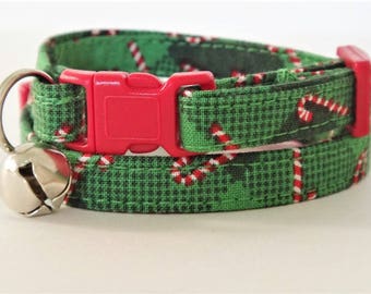 May include: Green and red cat collar with a candy cane pattern and a silver bell. The collar has a pink adjustable buckle.