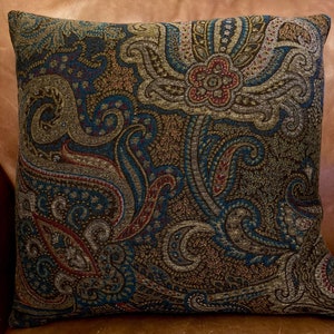 Puede incluir: Una almohada decorativa con un patr&oacute;n de paisley en tonos de marr&oacute;n, azul verdoso, dorado y rojo.