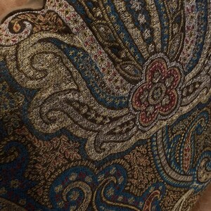 Puede incluir: Un coj&iacute;n de color marr&oacute;n, azul y crema con un patr&oacute;n de paisley y un dise&ntilde;o floral en el centro.