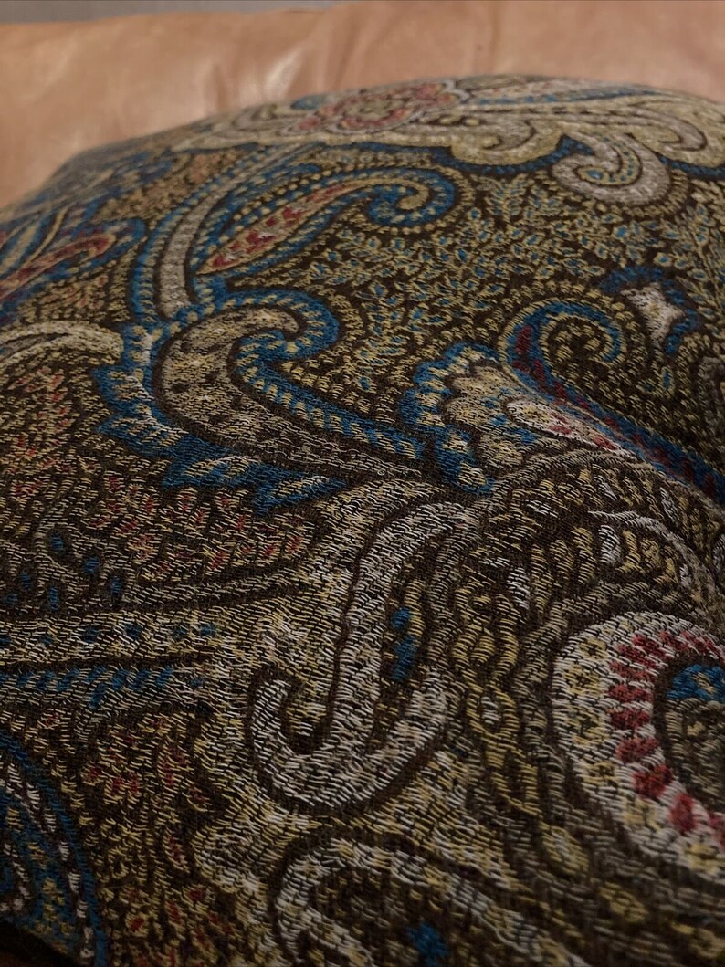 Puede incluir: Primer plano de una tela de color marr&oacute;n, azul y crema con estampado paisley. La tela tiene un aspecto texturizado y tejido.