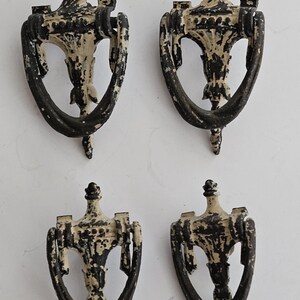 May include: Four antique door knockers with a black and white paint finish. The knockers are in the shape of a bell with a decorative top.