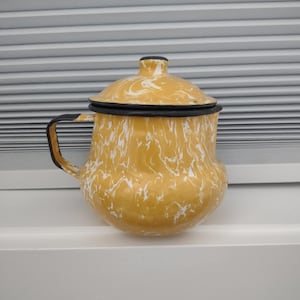 May include: Yellow enamelware coffee pot with a black handle and rim. The pot has a white marbled pattern. The lid is also yellow with a black rim and a small black knob. The pot is sitting on a white surface.