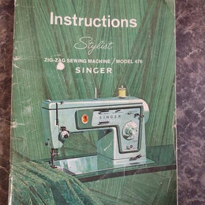 May include: A vintage instruction manual for a Singer Stylist Zig-Zag Sewing Machine Model 476. The cover features a green textured background, a light blue sewing machine illustration, and the text: Instructions Stylist ZIG-ZAG SEWING MACHINE / MODEL 476 SINGER What's new for tomorrow is at SINGER today!
