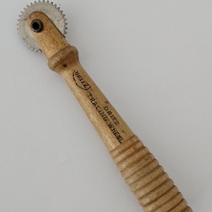 May include: A wooden tracing wheel with a metal wheel and a ribbed handle. The handle is labeled "DRITZ TRACING WHEEL".