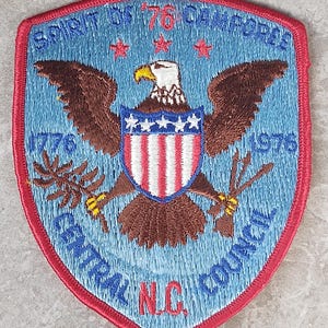 May include: Embroidered patch with a red border, featuring a blue background and a central design of an eagle with outstretched wings. The eagle holds arrows and a branch, with a shield in red, white, and blue. Text includes "SPIRIT OF '76 CA" and "CENTRAL COUNCIL N.C."