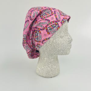 May include: Pink surgical scrub hat with a colorful print of hearts and the words "I love nursing".