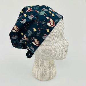 May include: A dark blue scrub hat with a Christmas-themed print featuring chickens, stars, and the text "Merry Christmas".