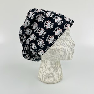 May include: Black scrub hat with a white print of cartoon ghosts and the text "BOO BOO CREW".