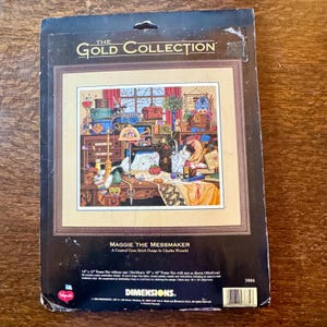 Può includere: Un kit per punto croce intitolato "Maggie the Messmaker" di The Gold Collection. Il kit presenta un'illustrazione dettagliata di un gatto in una stanza da cucito. La dimensione della cornice senza passe-partout è di 36 cm x 30 cm. Il kit è progettato da Charles Wysocki.