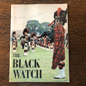 May include: A vintage book cover featuring a group of men in kilts and hats playing bagpipes. The cover is titled "The Black Watch" and has two signatures at the top.