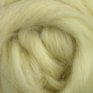 May include: Close-up of a mass of pale yellow fiber, likely wool or a similar material. The fibers are fine and densely packed, creating a soft, textured appearance. The color is a muted, natural tone, suggesting a raw or unprocessed state.