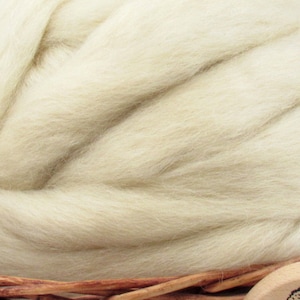 May include: A close-up of a pile of cream-colored wool roving. The roving is soft and fluffy, and it is perfect for spinning or felting.