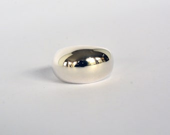 May include: A smooth, silver ring with a rounded, oval shape.
