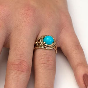 May include: A gold ring with a turquoise gemstone set in a cage-like design.