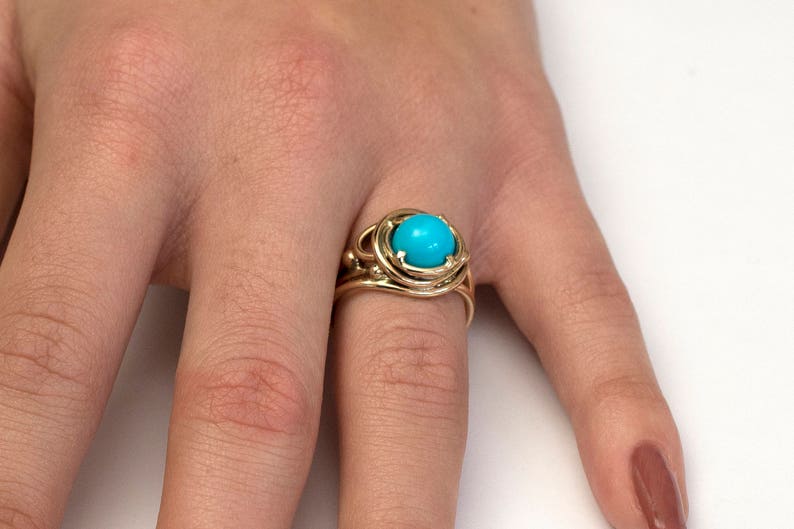 May include: A gold ring with a turquoise gemstone set in a cage-like design.