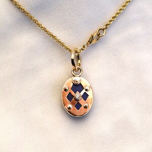 May include: A gold chain necklace with a pendant featuring a blue oval stone surrounded by a gold frame with a diamond in the center.