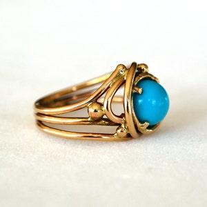 May include: A gold ring with a turquoise stone set in a delicate, intricate design.