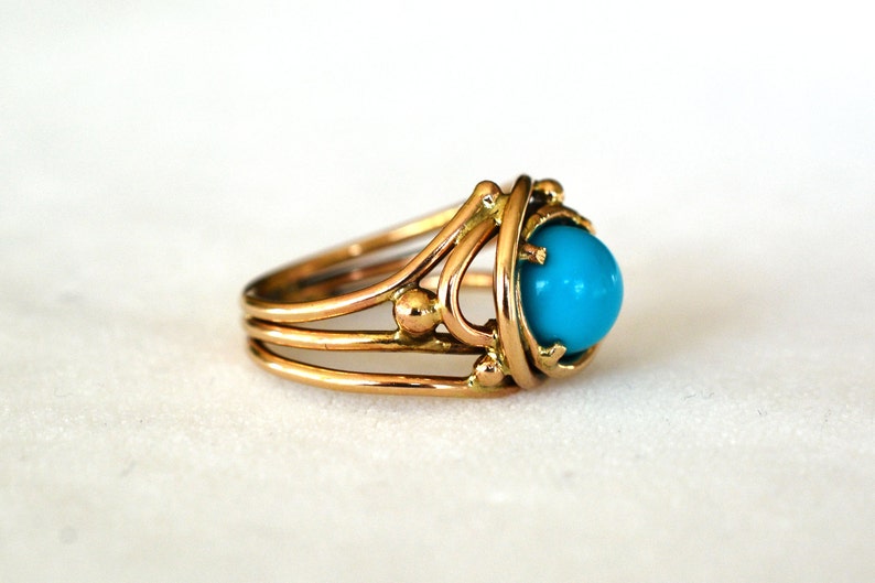 May include: A gold ring with a turquoise stone set in a delicate, intricate design.