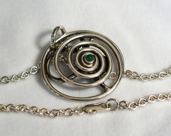 May include: A silver necklace with a spiral pendant featuring a green gemstone in the center.