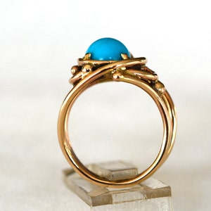 May include: A gold ring with a turquoise gemstone set in a twisted wire design.