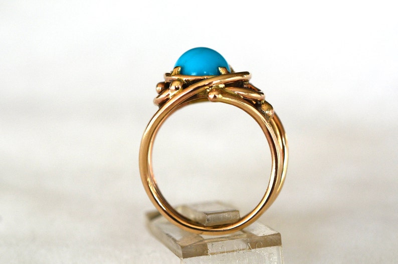 May include: A gold ring with a turquoise gemstone set in a twisted wire design.