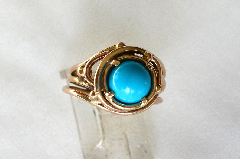 May include: A gold ring with a turquoise gemstone set in a delicate, intricate design.