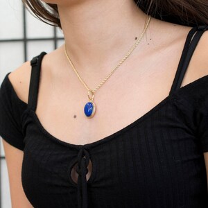 May include: A gold chain necklace with a blue oval pendant.
