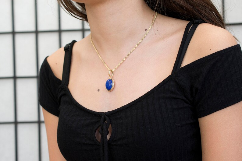 May include: A gold chain necklace with a blue oval pendant.