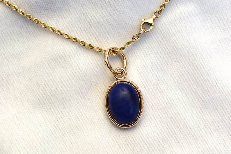 May include: A gold chain necklace with a pendant featuring a dark blue oval gemstone.