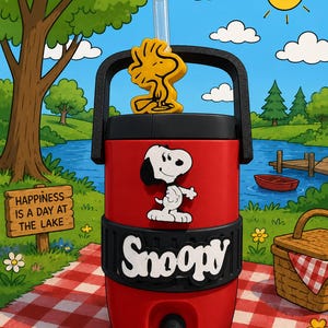 Może przedstawiać: Czerwony chłodziarka do napojów z czarną rączką i podstawą, ozdobiona białą grafiką Snoopy'ego oraz napisem "Snoopy" z przodu. Na górze znajduje się żółta nakładka w kształcie Woodstocka, a ze środka pokrywki wystaje przezroczysta słomka.