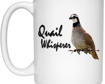 May include: White ceramic coffee mug with a brown and white quail perched on a barbed wire fence. The text "Quail Whisperer" is written in black cursive script.