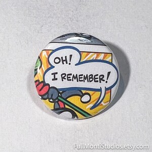 May include: A round button with a comic strip design. The button features a cartoon character holding a pole, with a speech bubble that says "OH! I REMEMBER!" The background is yellow, orange, and green.