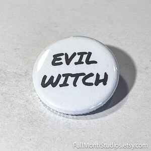 May include: A white button with the words "EVIL WITCH" in bold, black letters. The button has a glossy finish and a simple, clean design. The button is a fun accessory.