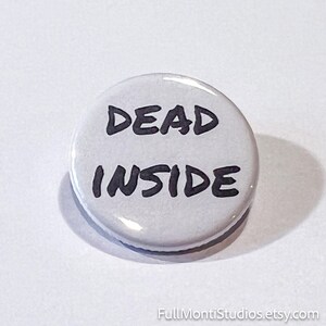 May include: A round, white button with the words "DEAD INSIDE" in bold, black letters. The button has a glossy finish and a shadow to the side. The Etsy shop name "FullMontiStudios.etsy.com" is at the bottom.