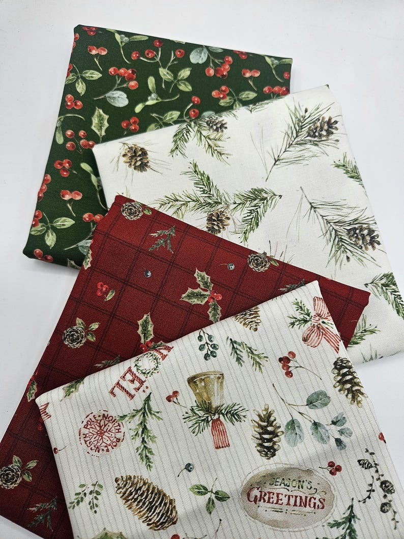 Pode incluir: Quatro quadrados de tecido dobrados com padr&otilde;es festivos. Um &eacute; verde-escuro com bagas vermelhas, um branco com ramos de pinheiro e pinhas, um vermelho-escuro com padr&atilde;o xadrez e azevinho, e um creme com sinos e texto.