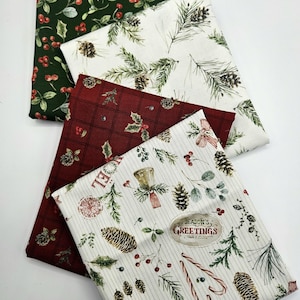 Pode incluir: Quatro quadrados de tecido dobrados com padr&otilde;es natal&iacute;cios. Um &eacute; verde-escuro com bagas vermelhas, um branco com ramos de pinheiro e pinhas, um vermelho-escuro com xadrez e um branco com bengalas doces, pinhas e texto.