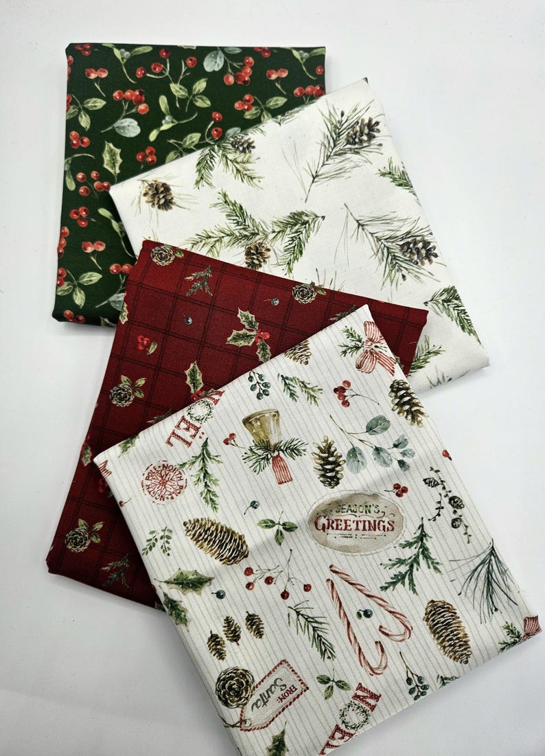 Pode incluir: Quatro quadrados de tecido dobrados com padr&otilde;es natal&iacute;cios. Um &eacute; verde-escuro com bagas vermelhas, um branco com ramos de pinheiro e pinhas, um vermelho-escuro com xadrez e um branco com bengalas doces, pinhas e texto.