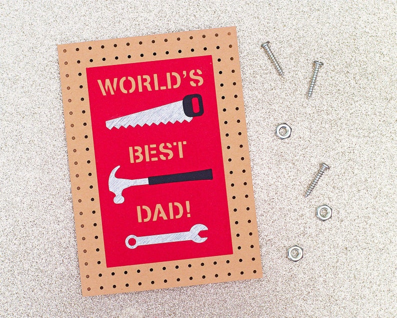 May include: A Father's Day card with a red background and the words "WORLD'S BEST DAD!" in white. The card features illustrations of a saw, hammer, and wrench. Three screws and three nuts are scattered around the card.