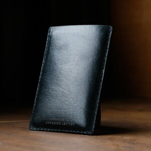 May include: A black leather phone case with the text "Handmade in the USA Kangaroo Leather" printed on the bottom.