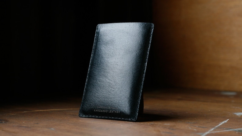 May include: A black leather phone case with the text "Handmade in the USA Kangaroo Leather" printed on the bottom.