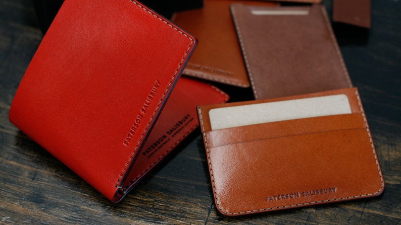 May include: Two leather wallets, one red and one brown, with the text "PATTERSON SALISBURY" embossed on them.