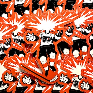 May include: A collection of orange and white stickers featuring a hockey player with a burst of energy emanating from the head. The player is wearing a Flyers jersey, black shorts, and white socks. The stickers are scattered.