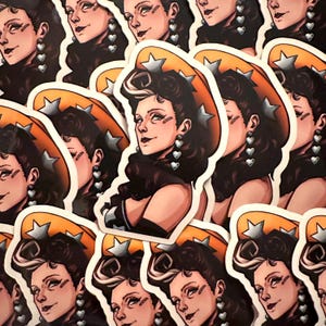 May include: A collection of stickers featuring a stylized illustration of a woman with dark hair, wearing a cowboy hat with star accents. She has heart-shaped earrings and a black top. The stickers have a white border.